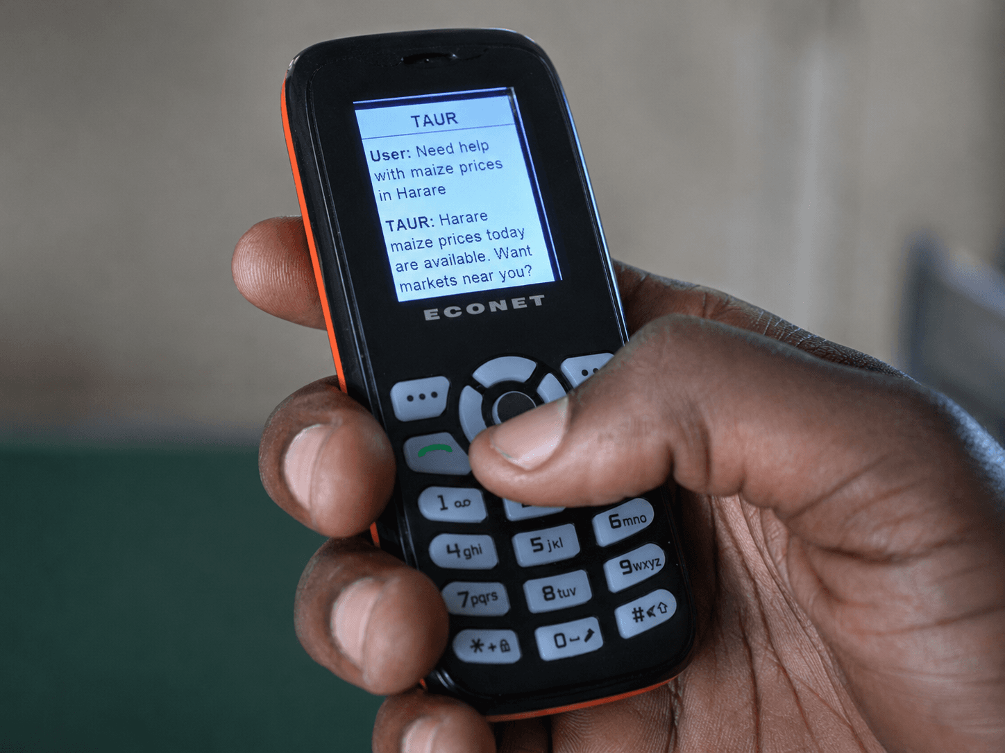 Feature phone showing a live TAUR SMS conversation